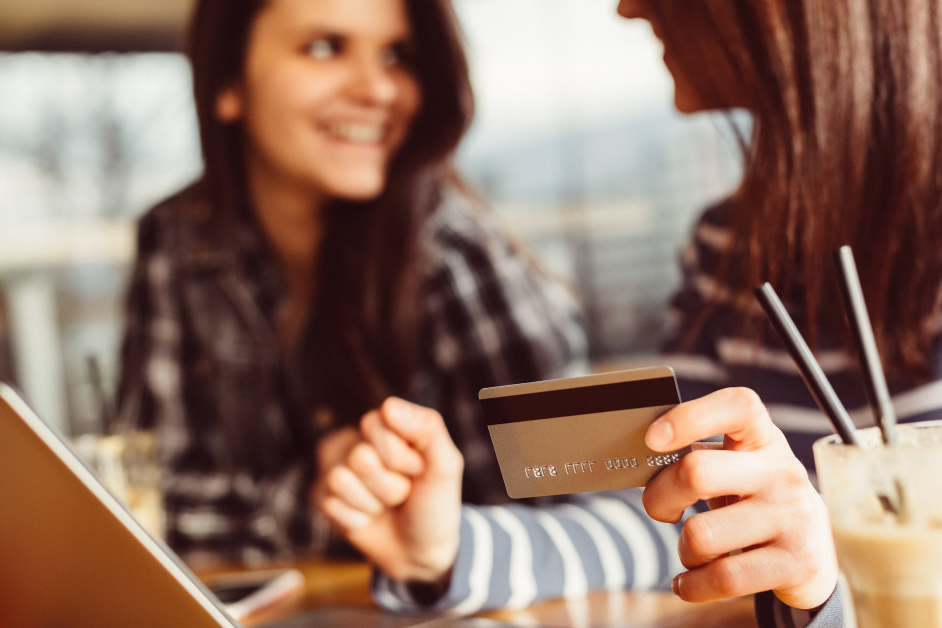 Junge Frauen trinken Kaffee und kaufen online ein